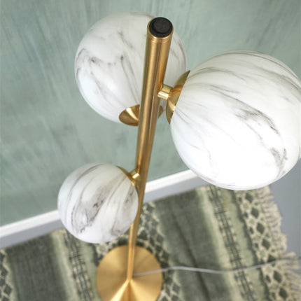 Vue de dessus des trois globes en verre effet marbre du lampadaire Carrara avec l'interrupteur manuel sur le tube