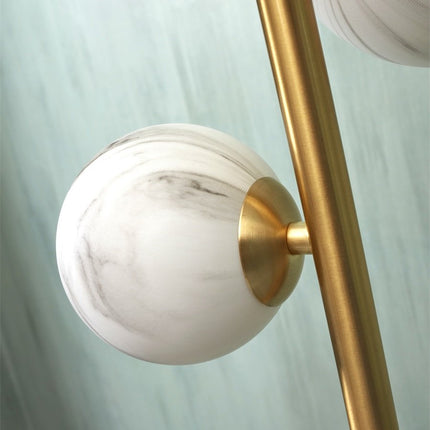 Détail de la fixation dorée reliant le globe en verre effet marbre à la tige du lampadaire Carrara