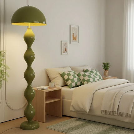Lampadaire champignon vert olive allumé dans une chambre douce à côté d'un lit habillé de lin