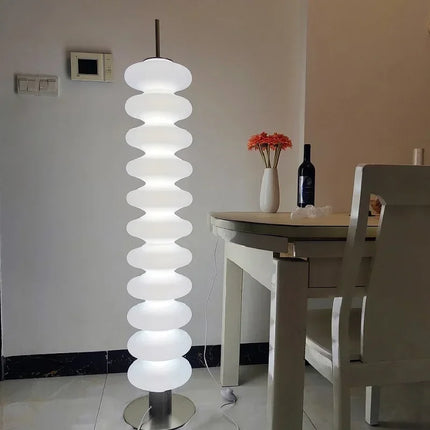 Lampadaire empilé blanc diffusant une lumière chaude dans un intérieur nordique