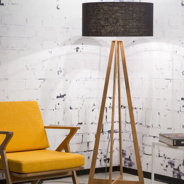 Lampadaire Everest en bambou avec abat-jour en lin noir, dans un salon avec fauteuil jaune et mur en briques blanches