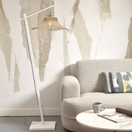 Lampadaire Ibiza en bambou tressé et structure blanche, installé près d'un canapé beige dans un salon lumineux