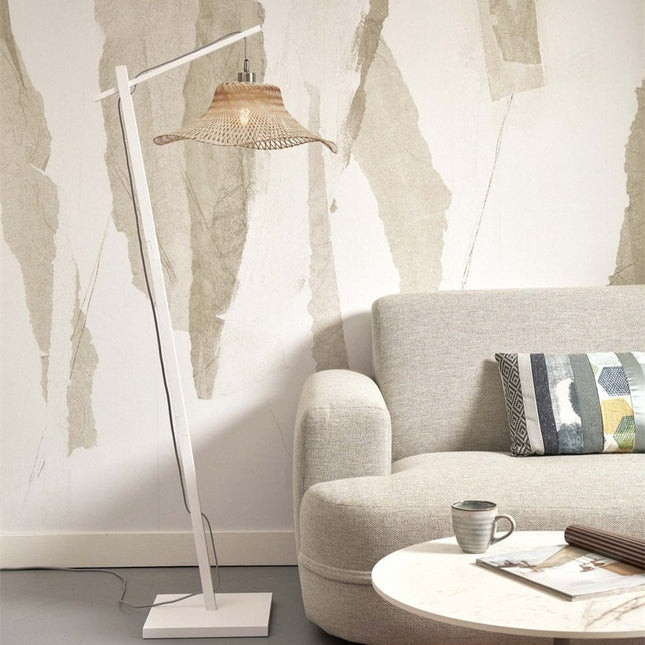 Lampadaire Ibiza en bambou tressé et structure blanche, installé près d'un canapé beige dans un salon lumineux