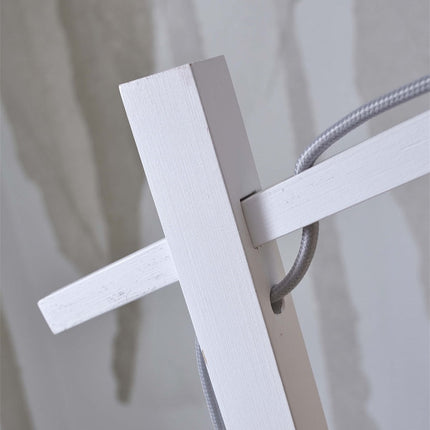 Détail de la jonction du bras oblique et du pied laqué blanc du lampadaire Ibiza, avec le câble textile gris
