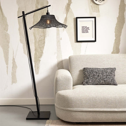 Lampadaire Ibiza en bambou tressé noir près d'un canapé beige, ambiance salon lumineuse et chaleureuse