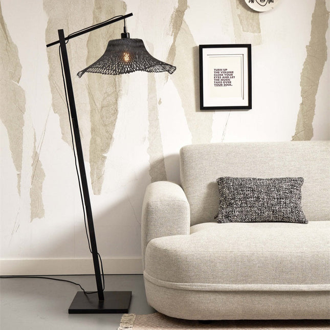 Lampadaire Ibiza en bambou tressé noir près d'un canapé beige, ambiance salon lumineuse et chaleureuse