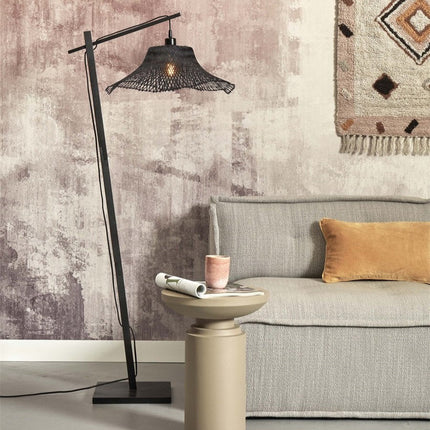 Lampadaire Ibiza bambou noir posé dans un salon cosy, à côté d'un canapé gris et d'une table d'appoint
