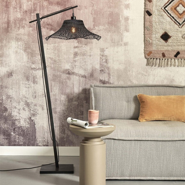 Lampadaire Ibiza bambou noir posé dans un salon cosy, à côté d'un canapé gris et d'une table d'appoint