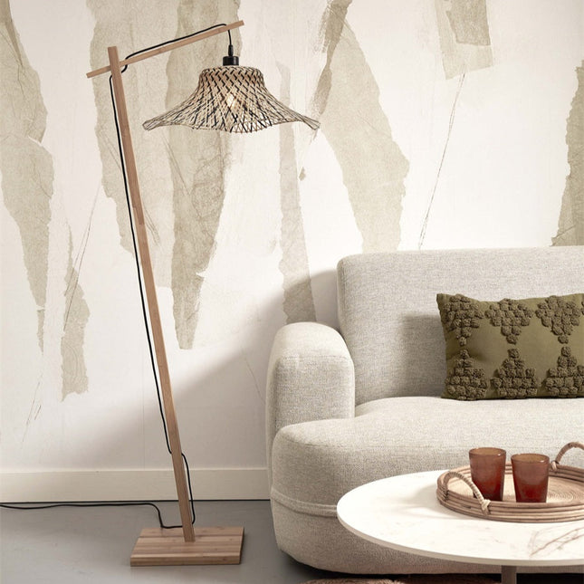 Lampadaire Ibiza en bambou tressé naturel et noir dans un salon lumineux, à côté d'un canapé en tissu clair