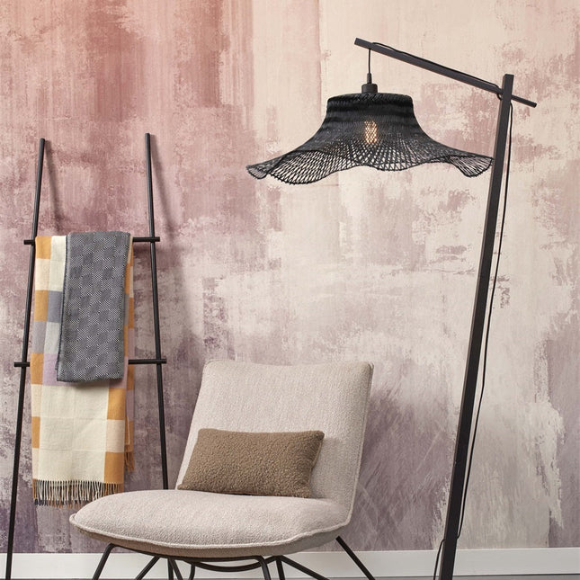 Lampadaire Ibiza en bambou tressé noir dans un salon, à côté d'un fauteuil beige et d'une échelle porte-plaid