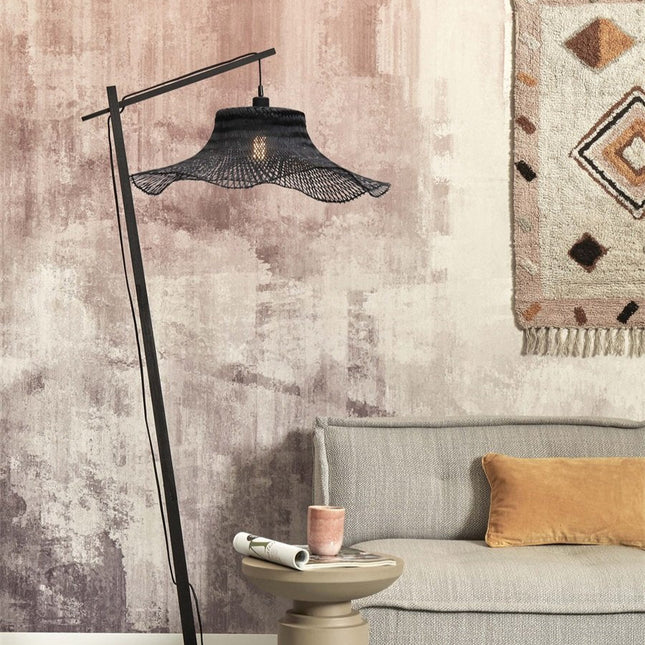 Lampadaire Ibiza sur pied en métal noir avec abat-jour en bambou tressé, éclairant un canapé gris et un tapis berbère