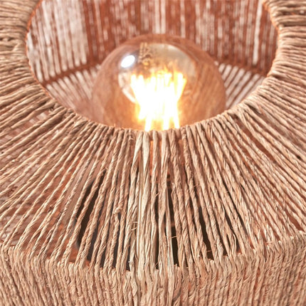 Vue du dessus de l'abat-jour en jute tressé, ampoule apparente diffusant une lumière chaude et enveloppante.