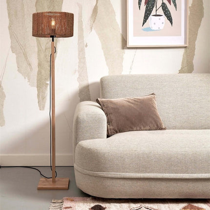 Lampadaire Iguazu posé à côté d'un canapé beige, apportant une lumière douce à l'ambiance du salon.