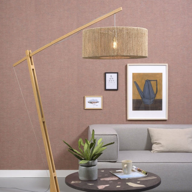 Lampadaire Iguazu en arceau, structure bambou naturel et abat-jour tressé jute, dans un salon à l'ambiance chaleureuse