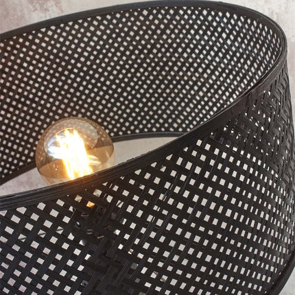 Jeux d'ombres tressées créés par la lumière filtrant à travers l'abat-jour en bambou noir du lampadaire Java