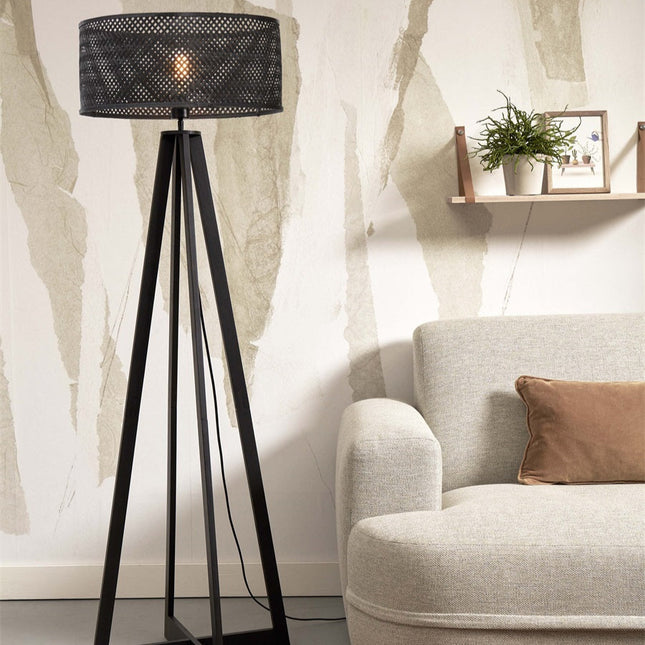Lampadaire Java bambou naturel posé au sol près d'un fauteuil en bois clair et tissu écru