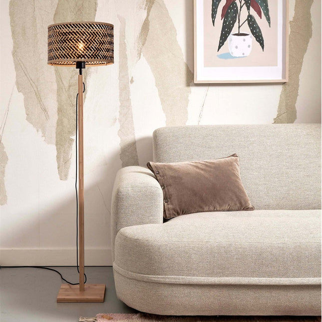 Lampadaire Java droit en bambou naturel et noir dans un salon, à côté d'un canapé beige