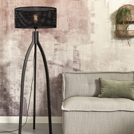 Lampadaire Java tripode en bambou noir avec abat-jour tressé, dans un salon aux tons rosés près d'un canapé