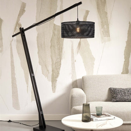 Lampadaire Java XL arqué en bambou noir dans un salon aux tons beiges, abat-jour allumé