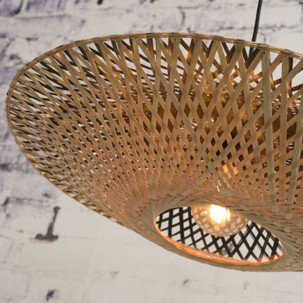 Dessous de l'abat-jour en bambou tressé noir et naturel du lampadaire Kalimantan, suspendu sur fond de mur en brique.