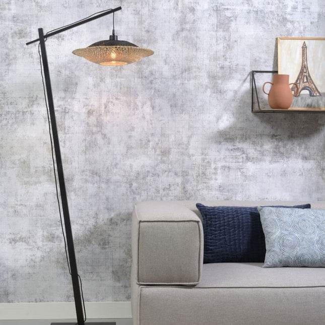Lampadaire liseuse Kalimantan en bambou tressé noir et naturel, installé près d'un canapé dans un salon cocooning.