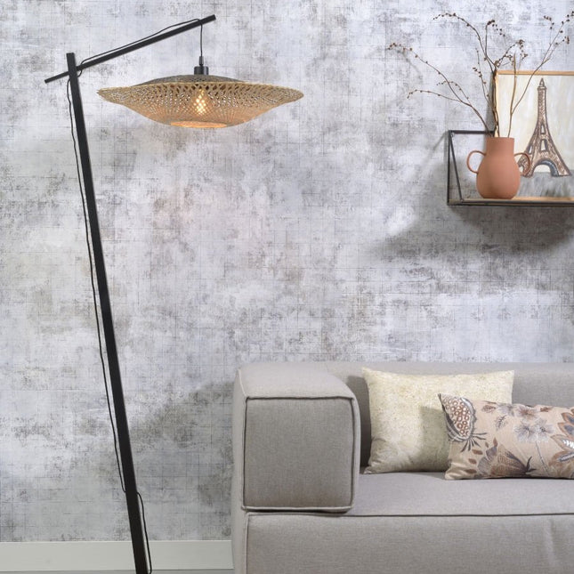 Lampadaire Kalimantan en bambou tressé et métal noir allumé dans un salon avec canapé gris