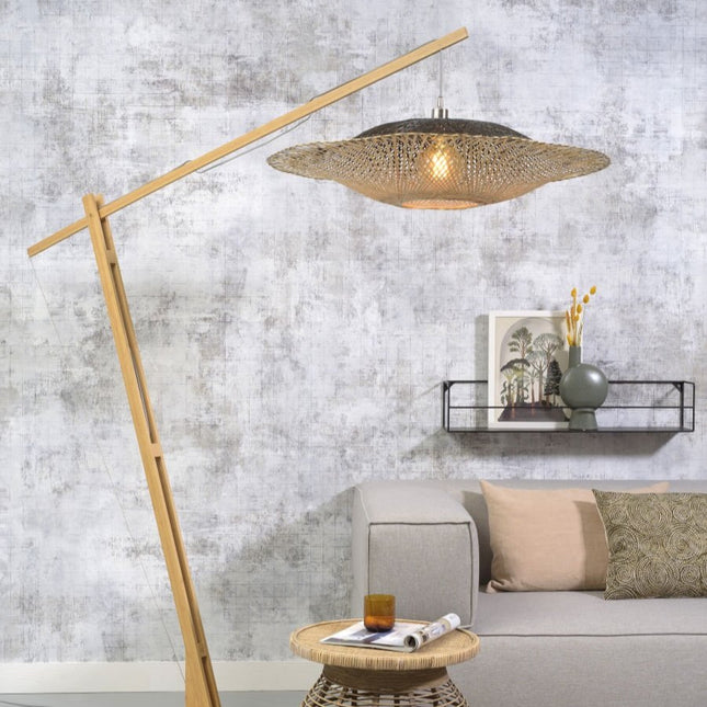 Lampadaire Kalimantan en bambou tressé naturel et noir, bras haut au-dessus d'un canapé dans un salon lumineux