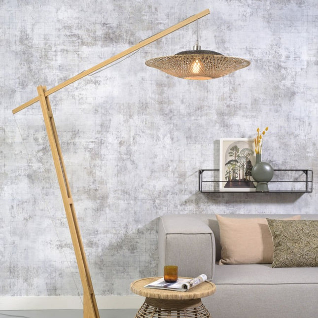 Lampadaire Kalimantan en bambou naturel et noir surplombant un salon avec canapé gris et étagère murale