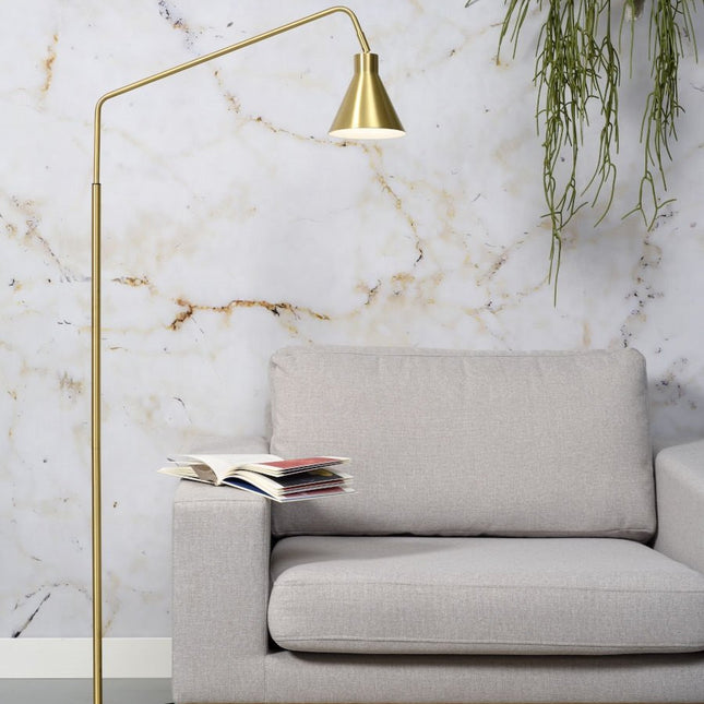 Lampadaire Lyon en fer doré, bras arqué et abat-jour conique au-dessus d'un canapé beige