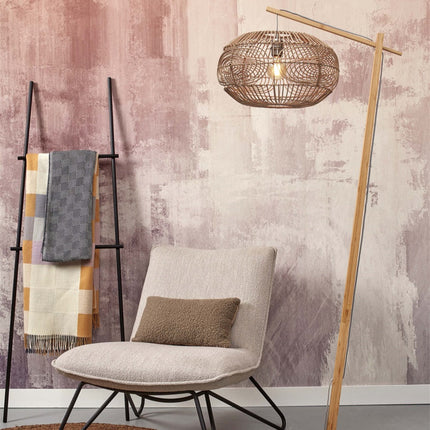 Lampadaire Madeira allumé, abat-jour en rotin tressé suspendu au-dessus d'un fauteuil beige