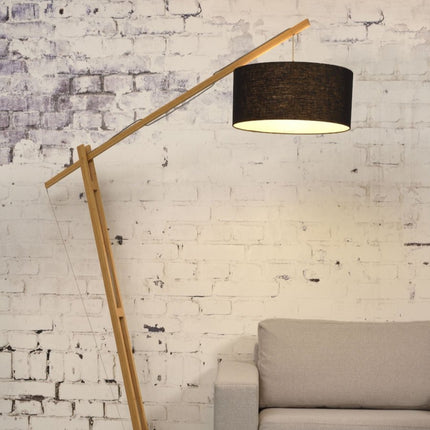 Lampadaire Montblanc en bambou naturel avec abat-jour en lin noir, dans un salon au mur brique blanchie