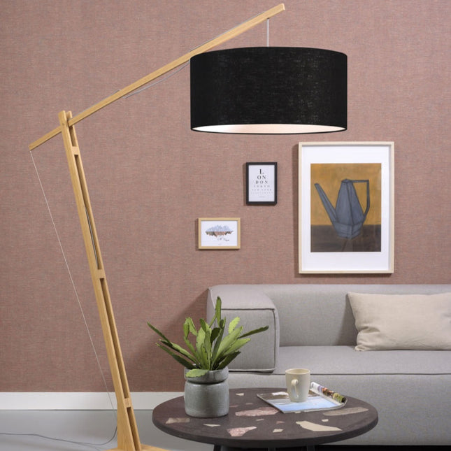 Lampadaire arqué Montblanc en bambou naturel et abat-jour en lin noir, dans un salon cocooning au mur rose poudré.