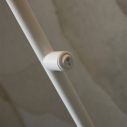 Détail de l'interrupteur rotatif blanc intégré sur la tige fine du lampadaire Porto en fer.