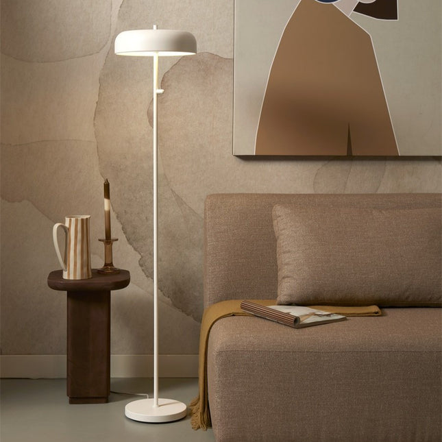 Lampadaire Porto fer blanc près d'un canapé beige, lumière douce et chaleureuse dans un salon cosy.