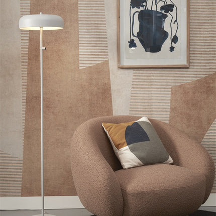 Lampadaire Porto gris clair allumé aux côtés d'un fauteuil rond dans un salon