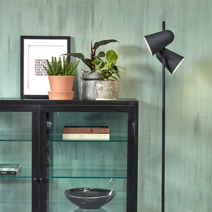 Lampadaire Salamanca noir allumé dans un salon près d'un meuble vitrine