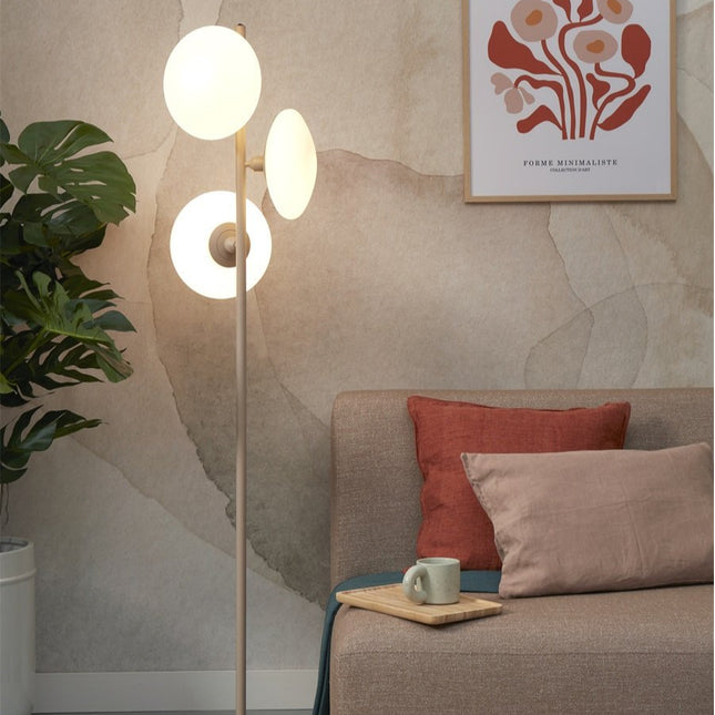 Lampadaire Sapporo 161 cm dans un salon, trois diffuseurs en verre blanc et mât sable