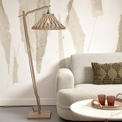 Lampadaire Tahiti bambou naturel et noir posé à côté d'un canapé beige et d'une table basse ronde
