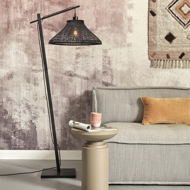 Lampadaire Tahiti en bambou tressé noir, bras déporté au-dessus d'un canapé dans un salon cosy