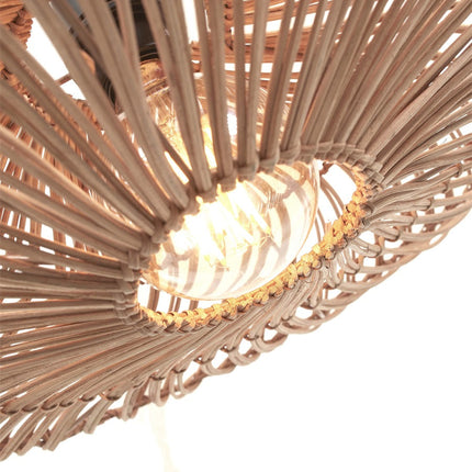 Vue en contre-plongée de l'abat-jour tressé du lampadaire Zanzibar, laissant apparaître l'ampoule et le jeu d'ombres du rotin.