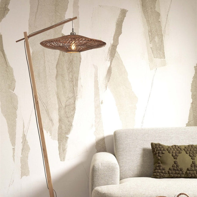 Lampadaire Zanzibar allumé dans un salon épuré, sa potence en bambou et son abat-jour tressé diffusant une lumière chaleureuse.