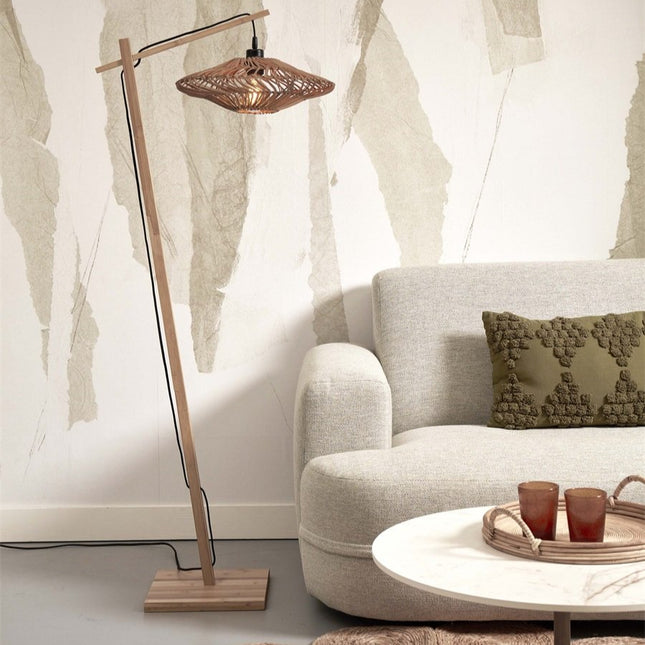 Lampadaire Zanzibar en bambou naturel et abat-jour rotin tressé, allumé dans un salon près d'un canapé beige