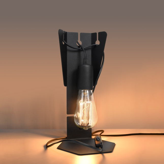 Lampe de bureau Arby en acier noir allumée, filament ambré diffusant une lumière chaude dans une pièce