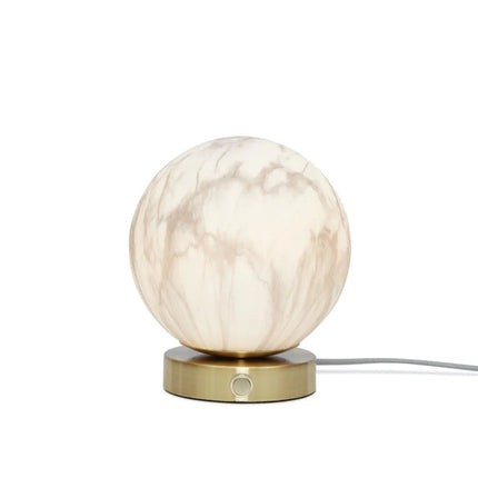 Lampe à poser Carrara globe marbre et or allumée en soirée, halo lumineux doux