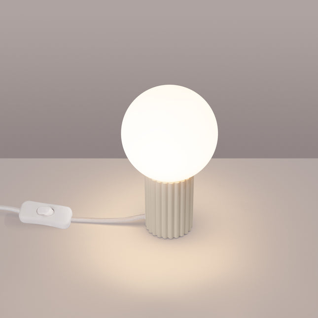 Lampe à poser Halo beige allumée, lumière chaude diffusée par le globe en verre opalin