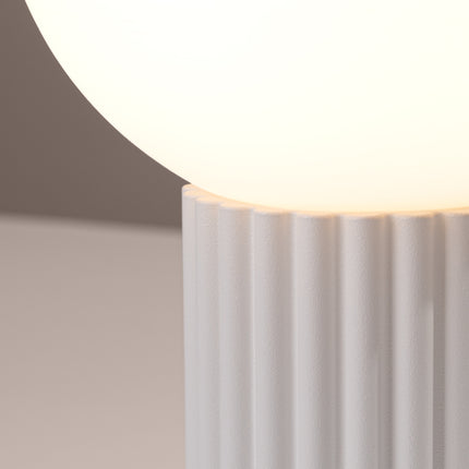 Détail des cannelures verticales du socle en aluminium blanc sous le globe en verre opalin