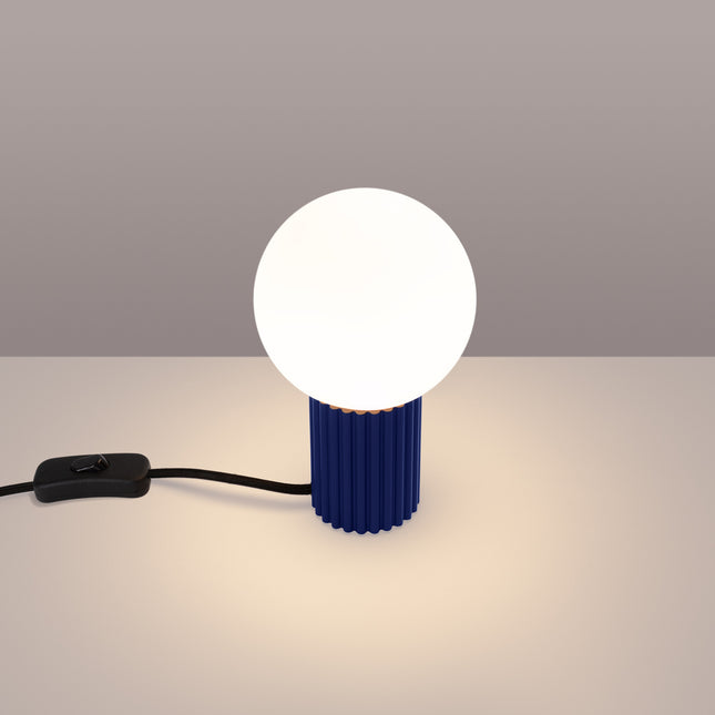 Lampe à poser Halo outremer allumée, lumière chaude diffusée par le globe en verre opalin