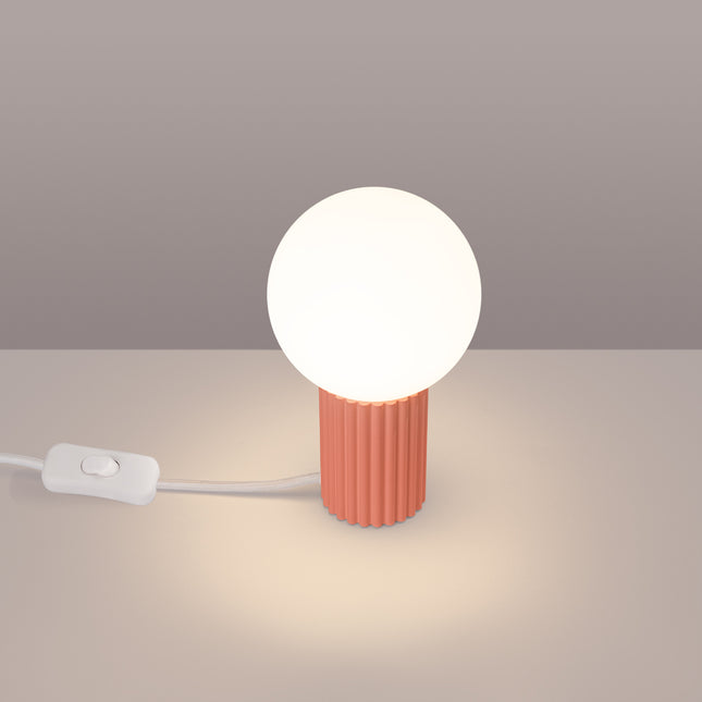 Lampe à poser Halo pêche allumée, lumière chaude diffusée par le globe en verre opalin