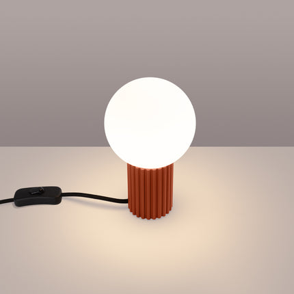 Lampe à poser Halo rouge ocre allumée, lumière chaude diffusée par le globe en verre opalin