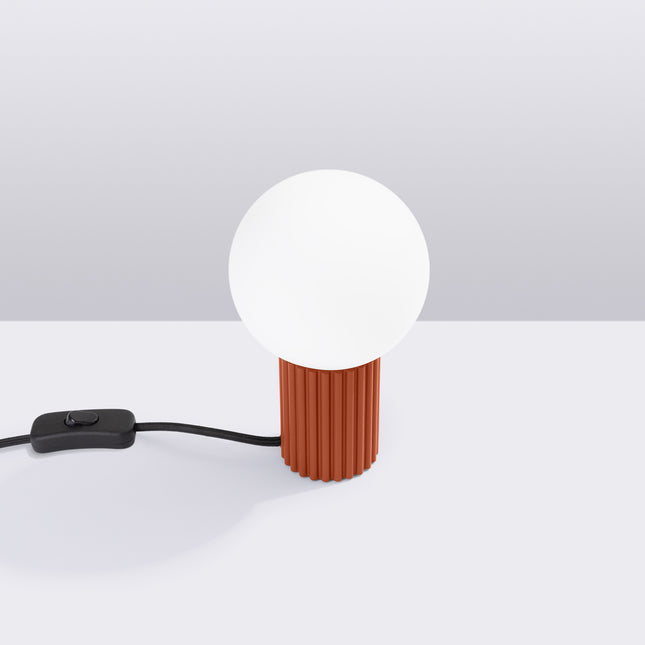 Lampe à poser Halo rouge ocre en situation studio, ambiance sur fond gris dégradé